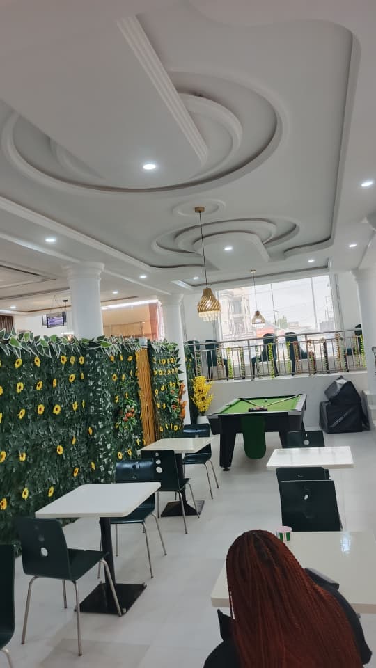Upper-floor lounge at Jogik with sunflower wall, dining tables and pool table