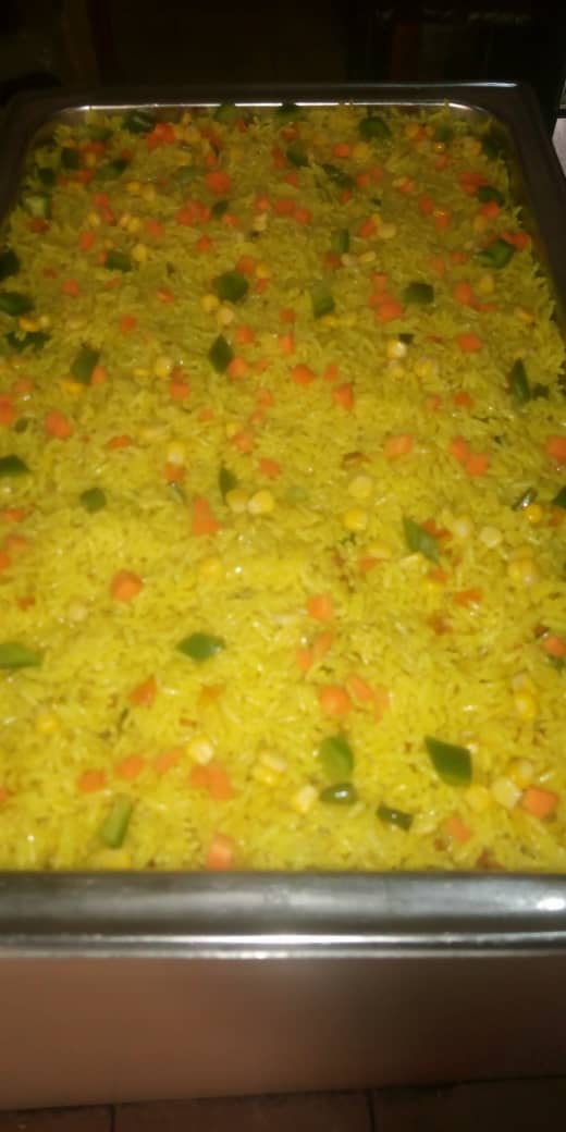 Full chafing dish of Jogik party jollof rice with peppers, carrots and sweet corn