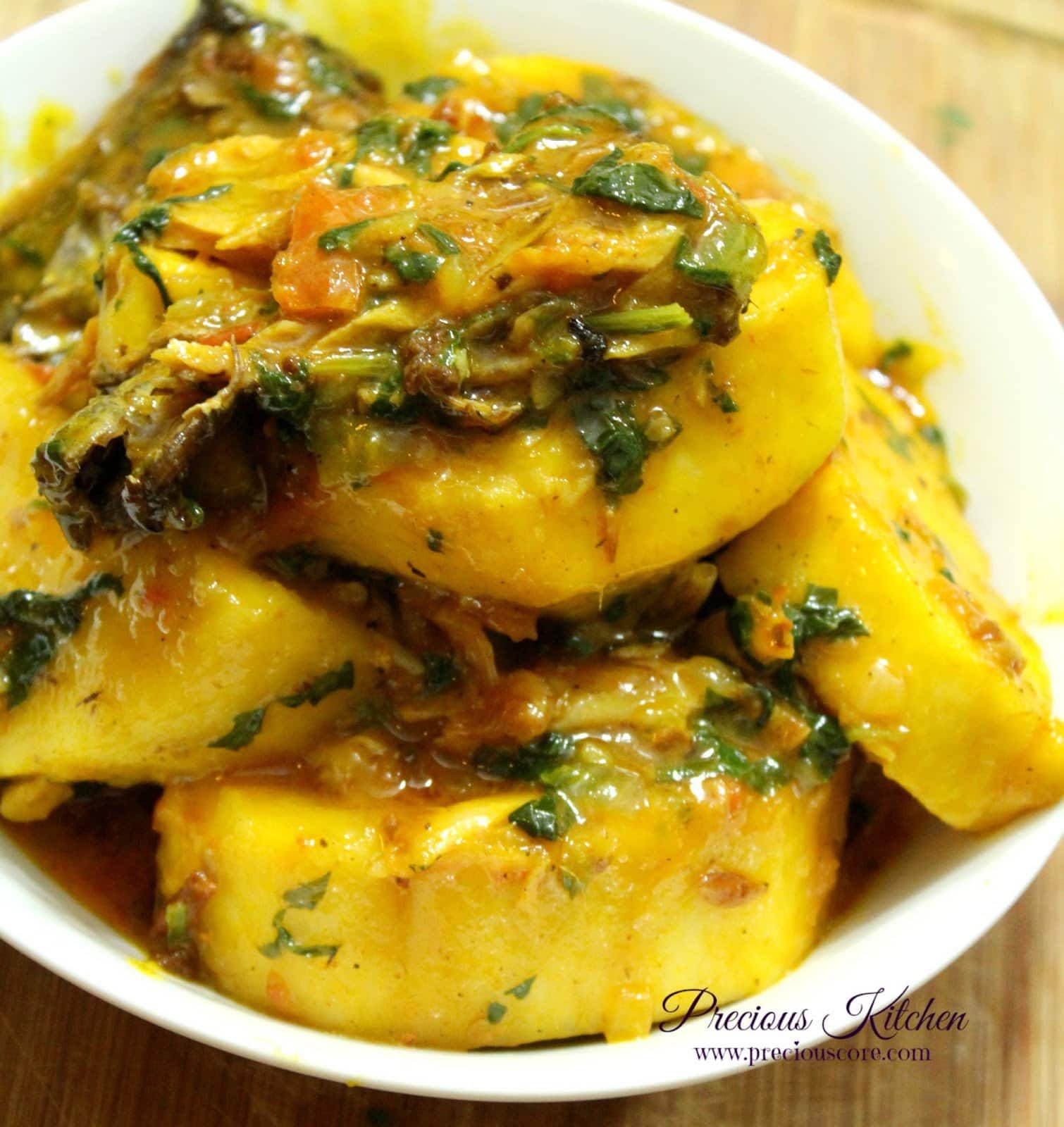 Nigerian yam porridge (Asaro) with dry fish and green leaves in an earthenware bowl