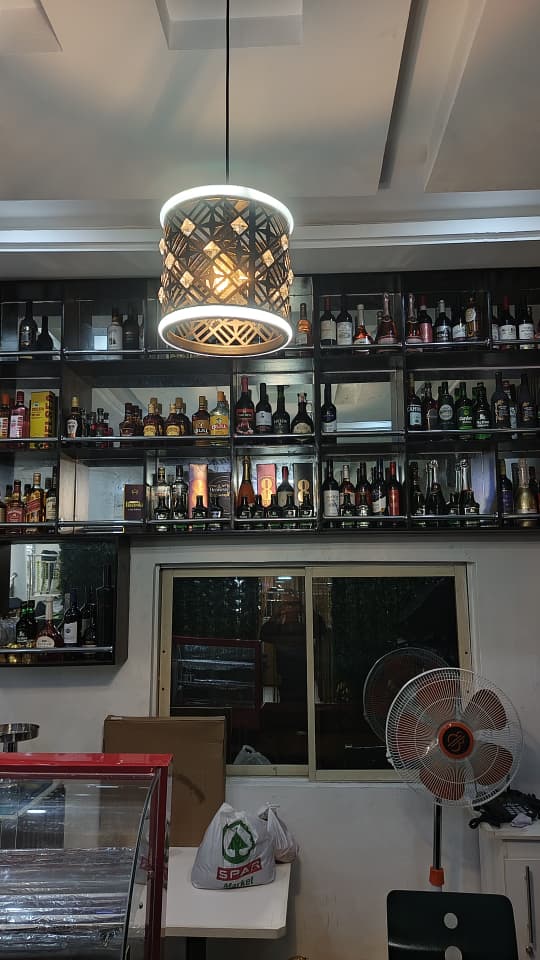 Full bar shelf at Jogik with wines, spirits and liqueurs under a pendant light